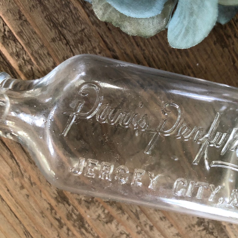 Puede incluir: Una botella de vidrio transparente con el texto "Davis's Dry-Lye" y "Jersey City, N.J." en relieve en el lateral.