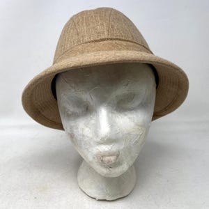 May include: A tan-colored hat with a rounded crown and a wide brim. The hat has a textured appearance and a dark band around the base of the crown. The brim measures approximately 2.5 inches.