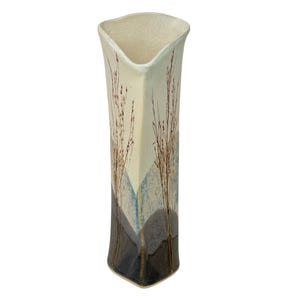 May include: A white ceramic vase with a geometric design and brown and blue brushstrokes. The vase has a wide mouth and a narrow base.