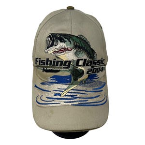 May include: A beige baseball cap with an embroidered image of a bass jumping out of the water. The text "Fishing Classic 2004" is embroidered on the front of the cap.
