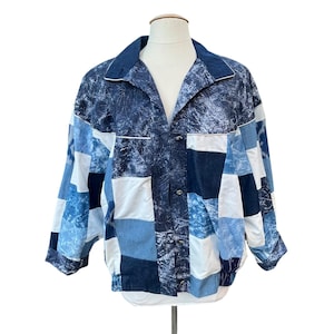 May include: A blue and white patchwork jacket with a button-up front and long sleeves. The jacket is made of different shades of blue denim and has a white background.