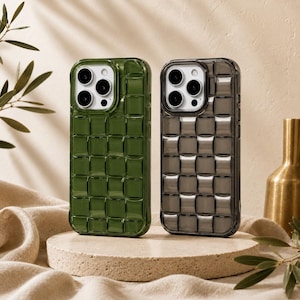Puede incluir: Dos fundas para smartphone con un patrón de rejilla tejida en relieve. Una funda es de color verde oscuro translúcido y la otra es de color gris carbón translúcido. Ambas tienen un recorte cuadrado para la cámara con tres lentes.