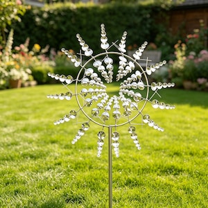 Könnte beinhalten: Ein silberfarbener Windspinner aus Metall mit einem kreisförmigen Rahmen und mehreren strahlenförmigen Speichen. Jede Speiche ist mit einer Reihe reflektierender, runder Scheiben besetzt, die nach außen hin kleiner werden.