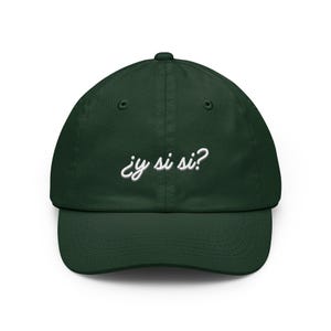 Puede incluir: Una gorra de béisbol de color verde bosque oscuro con el texto bordado en blanco ¿y si si? centrado en el panel frontal. La gorra cuenta con una corona estructurada, una visera curva y ojales verdes a juego para la ventilación.