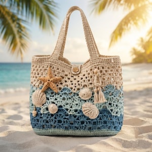 May include: A crochet tote bag featuring a gradient color scheme transitioning from beige at the top to light blue and dark blue at the base. The bag is decorated with a crocheted starfish, several seashell appliques, and a wooden bead tassel.
