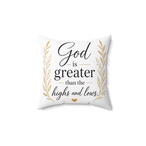 May include: A square white throw pillow featuring the black text God is greater than the highs and lows. The design includes two gold-coloured leafy branches framing the text on the left and right sides, with a small gold heart centred below.