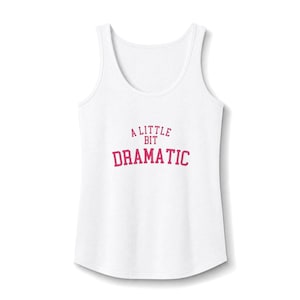 May include: A white sleeveless vest top featuring the text A LITTLE BIT DRAMATIC printed in a bold pink collegiate-style font across the centre of the chest. The garment has a scoop neckline and a standard fit with a curved hemline at the bottom.