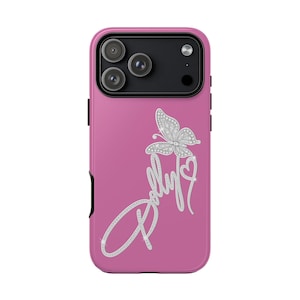 Könnte beinhalten: Eine pinkfarbene Smartphone-Hülle mit einer silbernen, strassartigen Grafik eines Schmetterlings, eines Herzens und dem kursiven Schriftzug Dolly. Die Hülle hat oben ein schwarzes Kameramodul mit drei Linsen und einem Blitz.