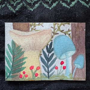 May include: A rectangular watercolour painting featuring a large beige mushroom, two smaller blue mushrooms, green fern-like foliage, and tiny red berries. The scene is set against a light background with brown vertical tree trunks on the sides.