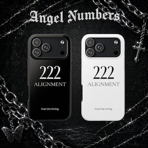 以下が含まれることがあります： 黒と白の2つのスマートフォンケース。それぞれに「222 ALIGNMENT」と「Trust the timing.」の文字が印字されています。ケースには3つのカメラ用カットアウトがあり、銀色のチェーンと十字架のチャームが飾られた暗い背景の前に配置されています。