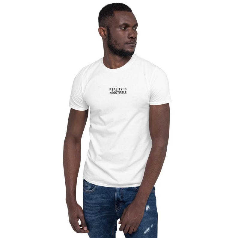 Man wearing the white Reality Is Negotiable embroidered tee with jeans