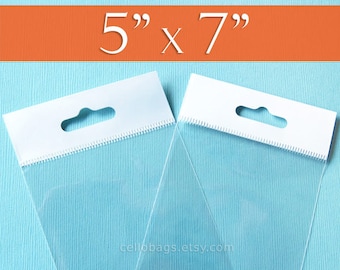 May include: Two clear cellophane bags with white header cards. The bags are 5" x 7" and have a hang hole. The bags are on a light blue background with an orange banner at the top that reads "5" x 7"". The website cellobags.etsy.com is at the bottom.
