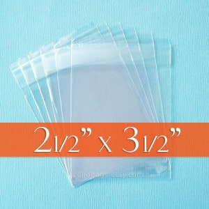 May include: A stack of clear cellophane bags, each measuring 2.5" x 3.5", are displayed against a light blue background. The bags are transparent and have a sealed top. The text "2 1/2" x 3 1/2"" is displayed on an orange banner.