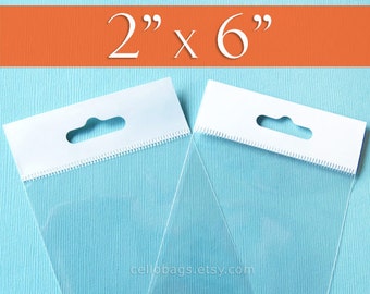 May include: Two clear cellophane bags with white header cards. The bags measure 2" x 6" and have a hang hole. The bags are on a light blue background with an orange stripe at the top. The text "2" x 6" is in white.