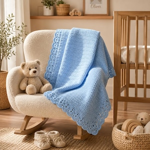 Könnte beinhalten: Eine hellblaue Häkeldecke mit gewelltem Rand, die über einen cremefarbenen Schaukelstuhl drapiert ist. Ein beigefarbener Teddybär sitzt auf dem Stuhl neben der Decke. Ein Paar kleine, cremefarbene Strickschühchen stehen auf dem Boden vor dem Stuhl.