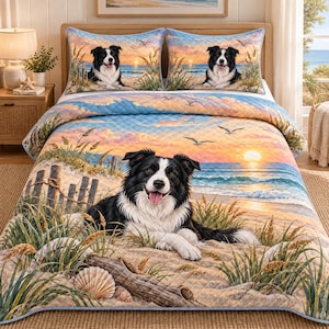 May include: A quilted bedspread and two matching pillow shams featuring a printed scene of a black and white Border Collie lying on a sandy beach at sunset. The design includes ocean waves, tall beach grass, a wooden fence, and flying seagulls.