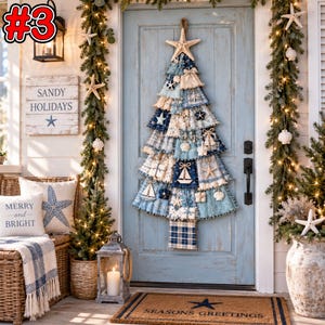 Könnte beinhalten: Ein Wand-Weihnachtsbaum aus geschichteten blauen und weißen Stoffstücken, verziert mit Seesternen, Muscheln und kleinen Segelboot-Ornamenten. Der Baum hängt an einer hellblauen Tür, flankiert von beleuchteten Tannengirlanden und Küstendekor.