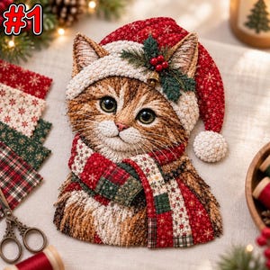 May include: A fabric appliqué of a brown tabby cat wearing a red and white quilted Santa hat with a small bell and holly sprig, and a matching patchwork scarf featuring red, green, and white snowflake and plaid patterns on a textured surface.