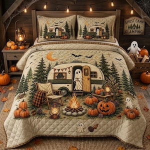 May include: A quilted bedspread and two matching pillow shams featuring a camping scene with a vintage camper, a ghost, pine trees, a campfire, and pumpkins. The design includes a crescent moon, bats, and a sign that reads Ghost Camp Glamping.