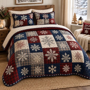 May include: A quilted bedspread and two matching pillow shams featuring a patchwork design of navy blue, deep red, and cream squares. Each square is decorated with white embroidered snowflake patterns, with some squares displaying a plaid texture.