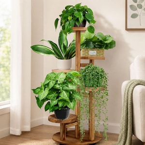 Puede incluir: Un soporte de madera para plantas de varios niveles con un poste central vertical y varios estantes circulares a diferentes alturas. El soporte sostiene cinco plantas de interior verdes, incluyendo una suculenta colgante y follaje.