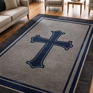 Puede incluir: Una alfombra rectangular que presenta un diseño de cruz grande y centrada en color azul oscuro sobre un fondo gris texturizado. La alfombra está enmarcada por una serie de bordes rectangulares anidados en tonos azul oscuro y gris.