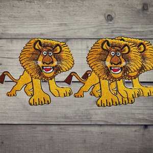 Op de afbeelding: Drie geborduurde leeuwenpatches met een cartoonachtig ontwerp met goudgeel bont, een grote bruine manen en een wijd open mond met witte tanden en een rode tong. Elke leeuw is afgebeeld in een staande positie met een lange staart.