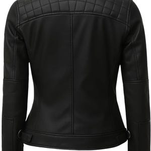 May include: A black jacket featuring a stand-up collar and a quilted panel across the upper back. The garment includes long sleeves with reinforced elbow sections, vertical seam detailing, and adjustable side tabs at the hem with metallic hardware.