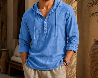 May include: A bright blue long-sleeve hooded shirt featuring a textured fabric, a partial button-down placket with two visible buttons, and thin matching drawstrings at the neckline, paired with light beige loose-fitting trousers.