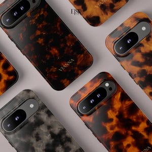 May include: Multiple smartphone cases featuring a glossy tortoiseshell pattern in shades of dark brown and amber, with some cases displaying a grey marbled effect. Each case includes a prominent horizontal camera cutout and the brand name VIANNA.
