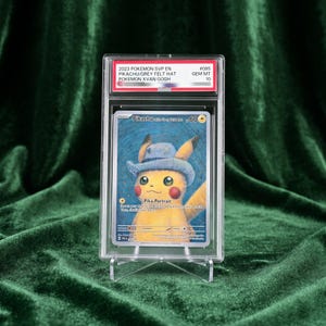 Peut inclure: Une carte à collectionner Pokemon SVP EN Pikachu with Grey Felt Hat de 2023, notée GEM MT 10. La carte représente un Pikachu jaune portant un chapeau bleu sur un fond bleu tourbillonnant, insérée dans un étui de protection en plastique rigide.