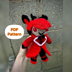 May include: A red and black crocheted plush toy with horns, a red coat, and white collar. The toy has red eyes and a black mouth. The text "PDF Pattern" is visible in the image.
