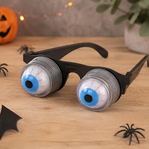 May include: Novelty glasses featuring two large, protruding blue eyeballs with red veins. The eyes are set within silver-coloured, spring-loaded cylindrical housings attached to a black plastic frame with standard temple arms for wearing.