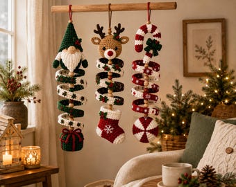 Peut inclure: Trois décorations de Noël en crochet suspendues à une tige en bois. À gauche, un gnome, au centre, un renne avec une chaussette, et à droite, une canne en sucre avec un disque mentholé. Chaque pièce possède un corps en spirale aux motifs festifs.