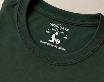 May include: A dark green t-shirt featuring a white graphic print on the inner neckline. The text reads I FUCKING LOVE YOU (either way works) with the names JACOB and QUEEN, a stick figure illustration, and THANKS FOR ALL THE ORGASMS.