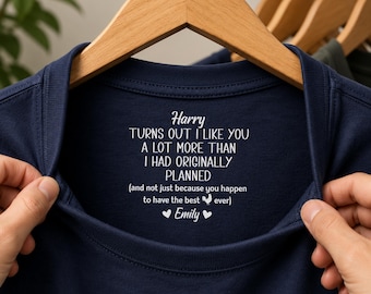 Könnte beinhalten: Ein marineblaues T-Shirt mit weißem Aufdruck im Innenkragenbereich, der lautet: Harry TURNS OUT I LIKE YOU A LOT MORE THAN I HAD ORIGINALLY PLANNED (and not just because you happen to have the best chicken ever) Emily.