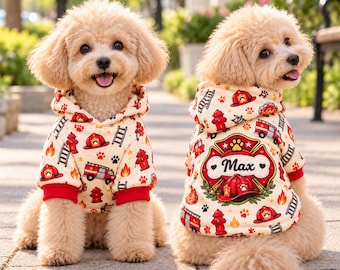 May include: Two light-colored curly-haired dogs wearing cream-colored hooded sweatshirts with a red and black firefighter-themed pattern featuring fire trucks, hydrants, and ladders. The back of one sweatshirt displays the name Max.