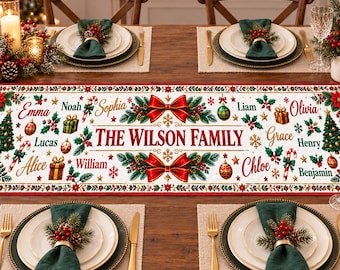 May include: A rectangular white table runner featuring a festive Christmas design with red bows, green pine branches, candy canes, ornaments, and gift boxes. The text THE WILSON FAMILY is printed in the center, surrounded by various names.