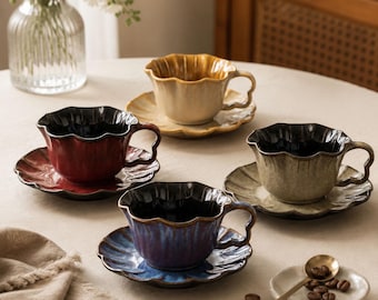 May include: Four ceramic teacups with matching saucers in yellow, red, green, and blue, each featuring a scalloped rim and a glossy finish. The cups have a dark interior and a curved handle. A small plate with coffee beans and a spoon are included.
