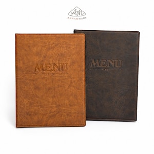 May include: Two rectangular menu covers with a textured finish. One cover is light brown and the other is dark brown. Both feature the word MENU embossed in the centre with a decorative line underneath. The logo ANNAMMADE is at the top.