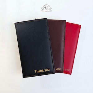 May include: Three rectangular bill presenters in black, dark brown, and red, each featuring visible stitching along the edges and the words Thank you embossed in gold lettering at the bottom. The logo ANNAMMADE is visible at the top centre.