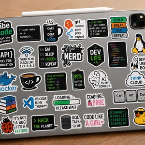 Peut inclure: Une tablette grise recouverte d'une vari&eacute;t&eacute; d'autocollants en vinyle color&eacute;s sur le th&egrave;me de la programmation et de la technologie. Les autocollants incluent des textes comme Vibe Code, Eat Sleep Code Repeat, Dev Life, AI is My Copilot et des ic&ocirc;nes.