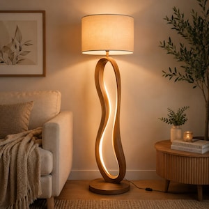 Puede incluir: Una lámpara de pie con pantalla cilíndrica de tela beige y base de madera clara curvada. La base cuenta con una tira de luz vertical integrada que ilumina el centro hueco de la estructura, apoyada sobre una base de madera circular.