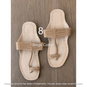 Op de afbeelding: Een paar beige leren sandalen met een teenstuk, een brede horizontale band met decoratieve stiksels en een platte zool. De tekst 8 en Beige Colour zijn zichtbaar op de afbeelding. De sandalen hebben een lichte kleur en een eenvoudig ontwerp.