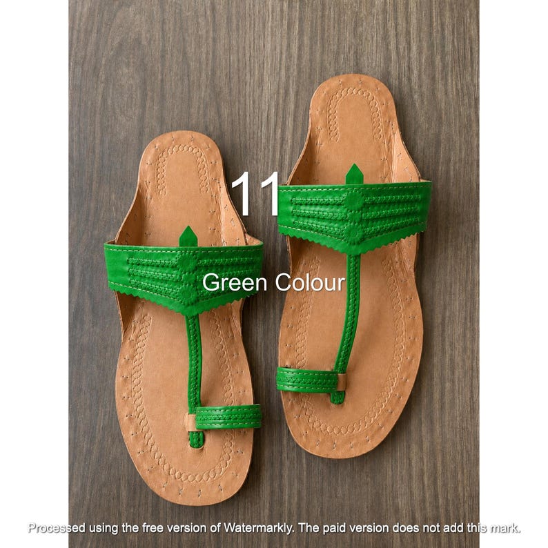 Op de afbeelding: Een paar platte sandalen met een beige leren voetbed, decoratieve stiksels langs de randen en een felgroene leren band over de wreef. Het ontwerp bevat een teenlus en een centrale verticale band. Tekst: 11 Green Colour.