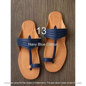 Op de afbeelding: Een paar marineblauwe sandalen met een lichtbruin voetbed en decoratieve stiksels langs de randen. De marineblauwe band heeft een teenstuk en een geschulpte rand met cirkelvormige details. De tekst 13 en Navy Blue Colour zijn zichtbaar.