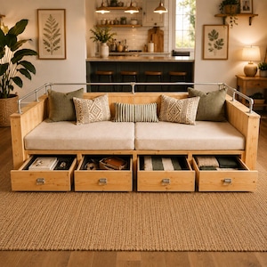 May include: A light wood daybed featuring a metal pipe railing, beige seat cushions, and four pull-out storage drawers underneath. The daybed is decorated with two solid olive green square pillows, two patterned beige square pillows, and one striped lumbar pillow.