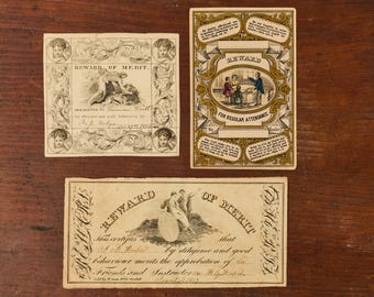 May include: Three vintage Reward of Merit cards featuring intricate black and white engravings of figures and cherubs, alongside a gold-toned rectangular card with a central illustration of children and text including Bible verses and attendance notes.