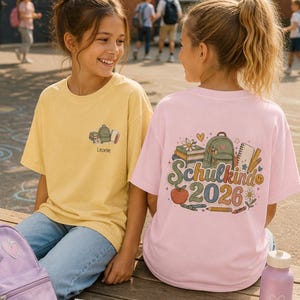 Puede incluir: Una camiseta amarilla con un pequeño gráfico de mochila y libros y el nombre Leonie en el frente, y una camiseta rosa con un gráfico escolar grande que presenta una mochila, libros y el texto Schulkind 2026 en la parte posterior.