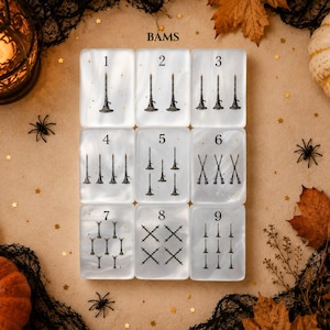 May include: A set of nine rectangular white translucent tiles arranged in a grid, each featuring black illustrations of witch hats and broomsticks. The tiles are numbered one through nine, with varying quantities of the illustrated icons on each tile.
